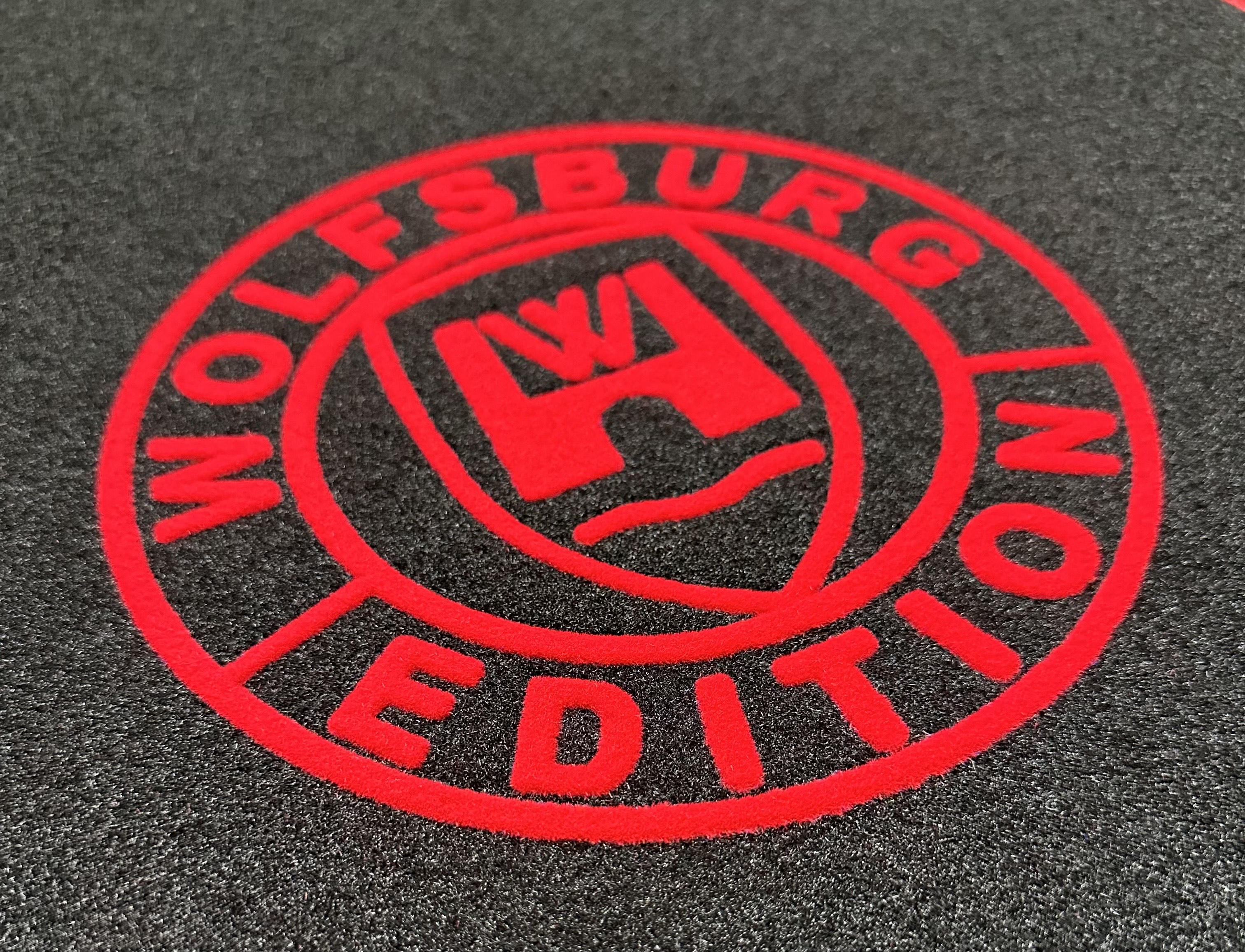 Das Wolfsburg Edition logo auf schwarzem Teppich in rot.