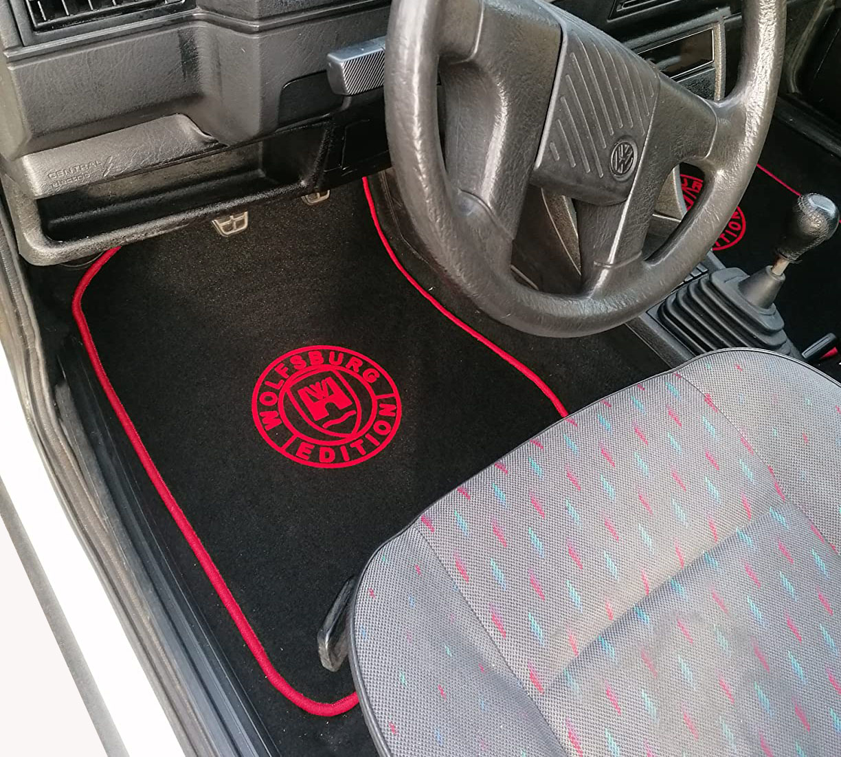 Der Fussraum eines VW Golf 2 mit einer Wolfsburg Edition Fussmatte in schwarz mit rot.